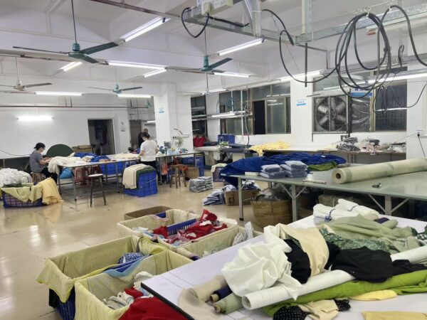Fabric rolls and garment bundles arranged around clothing workshop tables