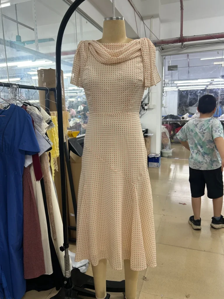Beige textured midi dress with a draped cowl neckline and short sleeves on a mannequin.