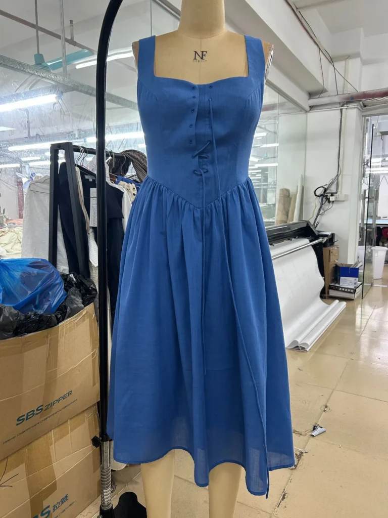 Blue sleeveless midi dress with a square neckline and gathered waist on a mannequin.