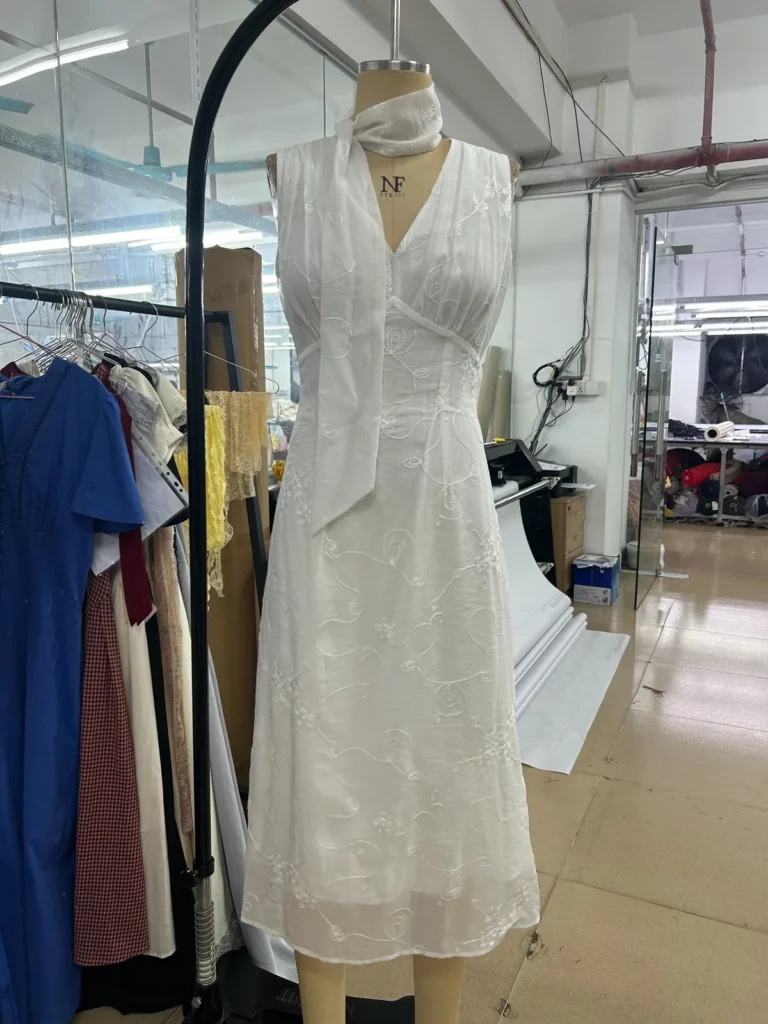 Ivory sleeveless midi dress with a V-neck and gathered bodice on a mannequin.