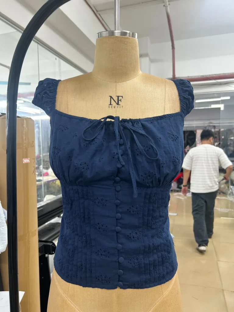 Navy fitted top with a gathered square neckline and tie detail on a mannequin.