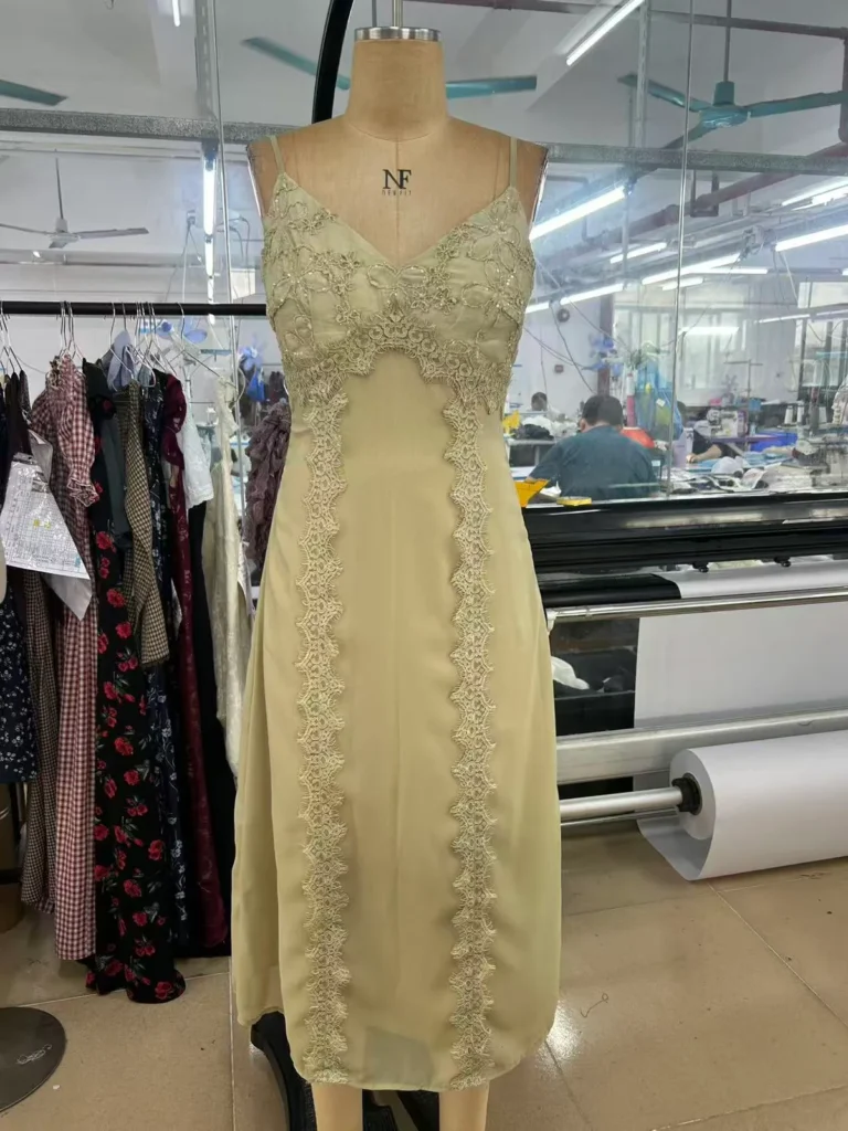 Pale yellow midi dress with shoulder straps and vertical lace trim on a mannequin.
