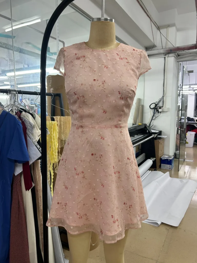 Pink floral mini dress with cap sleeves and a fitted waist on a mannequin.