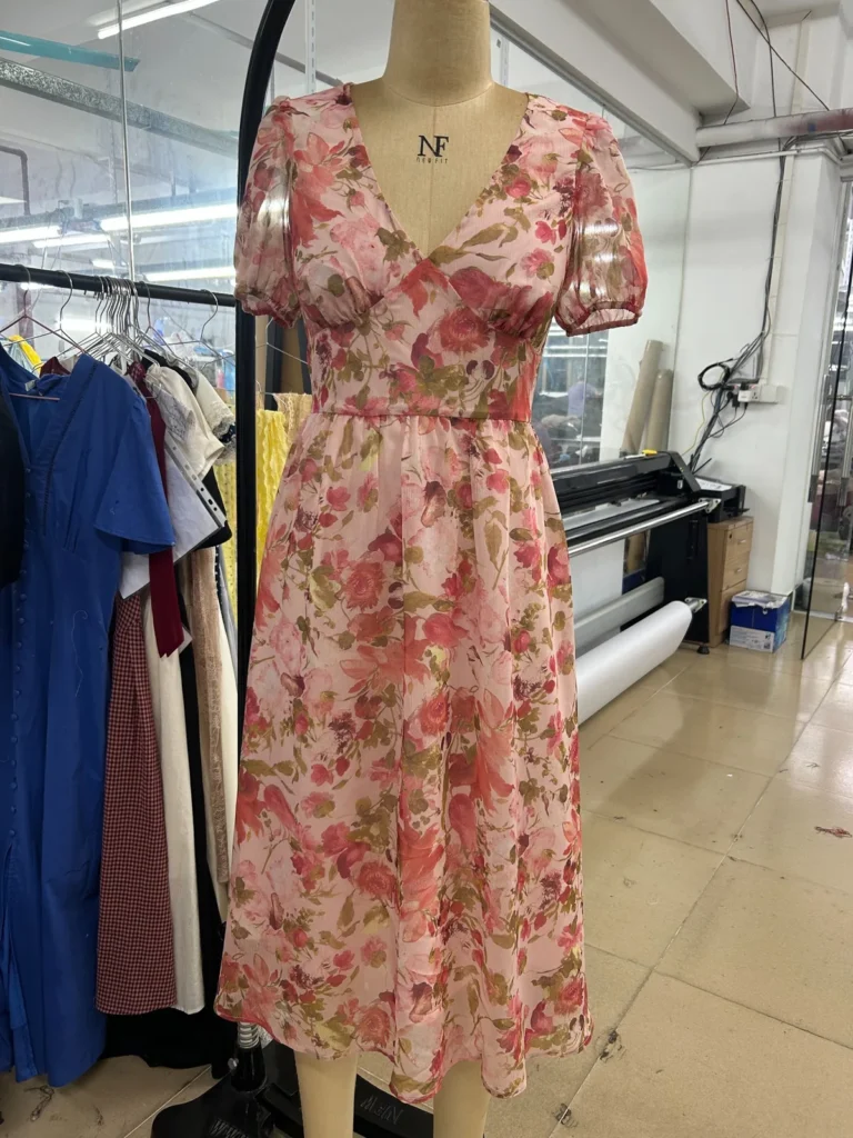 Pink floral midi dress with a V-neck and short sleeves on a mannequin.