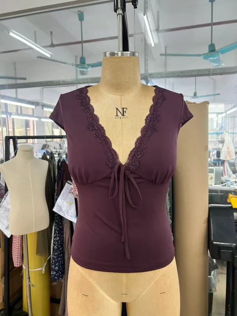Plum fitted top with a lace-trim V-neck, cap sleeves and front tie on a mannequin.