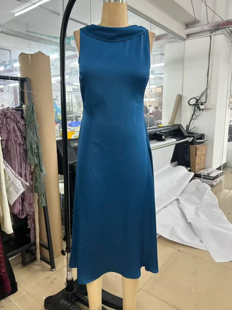 Teal sleeveless midi dress with a draped cowl neckline on a mannequin.