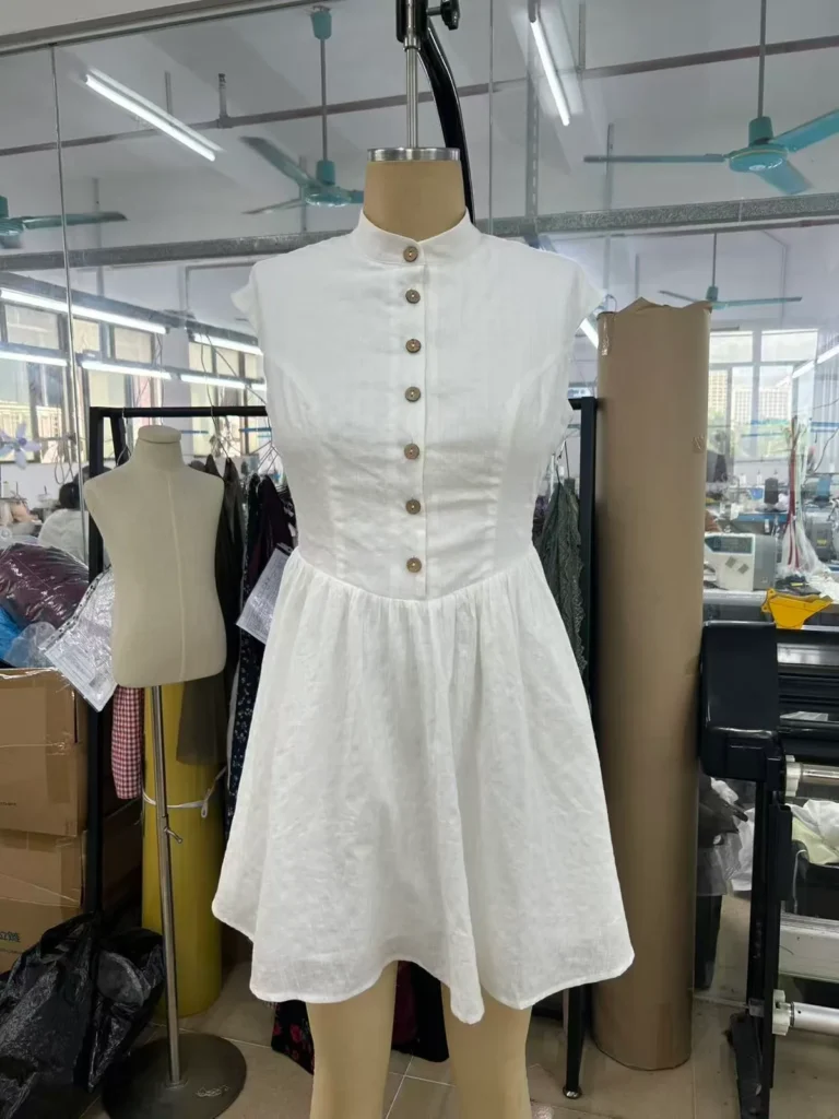 White mini dress with a stand collar, button front and cap sleeves on a mannequin.