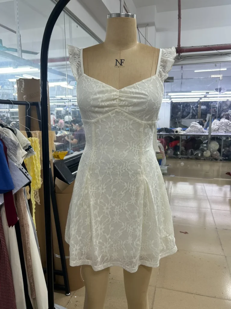 White mini dress with a ruched bodice and shoulder straps on a mannequin.