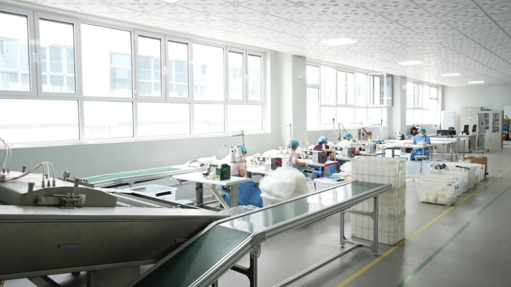 A modern factory interior with workers operating sewing machines under bright lighting.