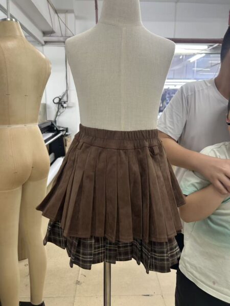 Brown pleated mini skirt with a check-pattern hem on a mannequin