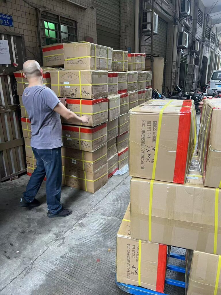 Worker handling strapped cartons in an outdoor loading area beside the building