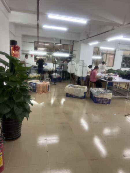 View past a potted plant toward garment work tables and storage baskets