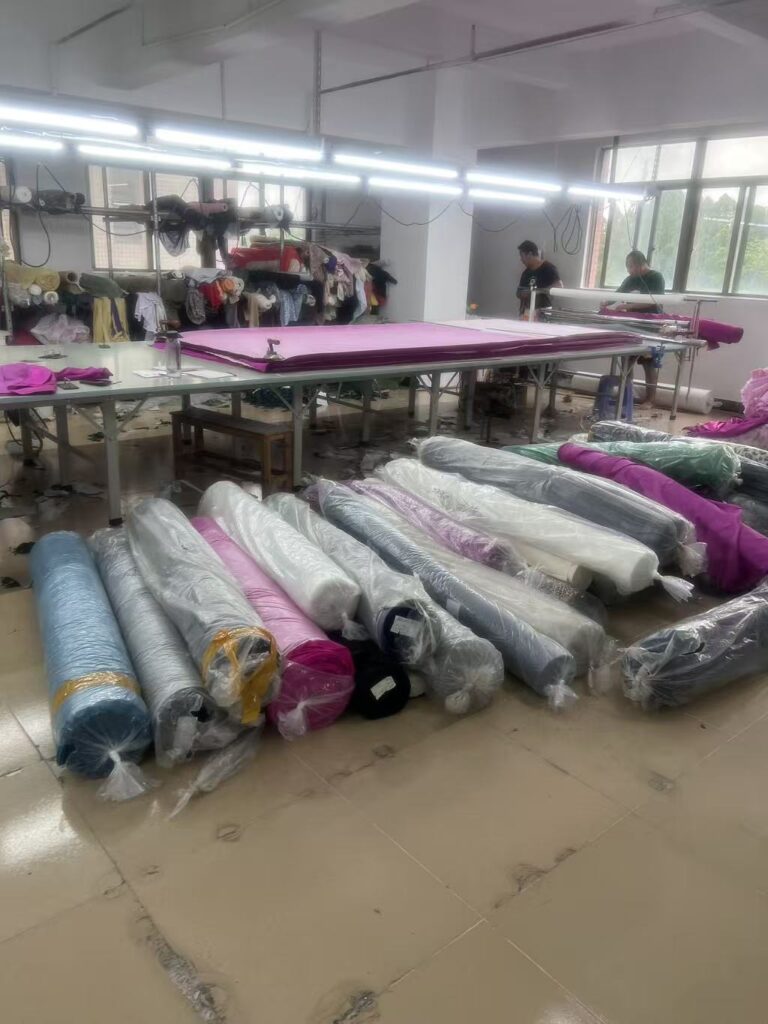 Fabric rolls beside a cutting table in a garment factory