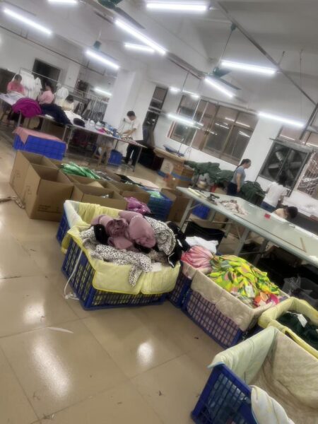 Baskets of colorful garments beside finishing tables and open cartons