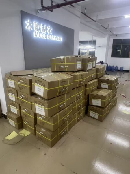 Stacks of sealed and strapped cartons beneath the garment company wall sign