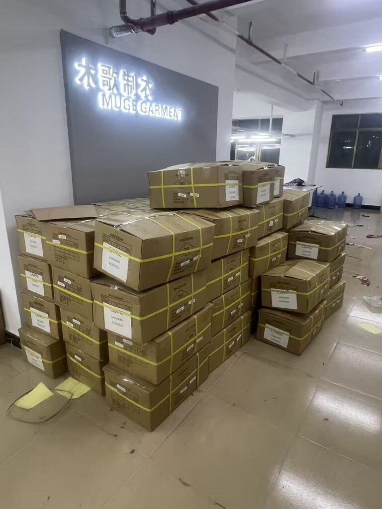 Stacks of sealed and strapped cartons beneath the garment company wall sign