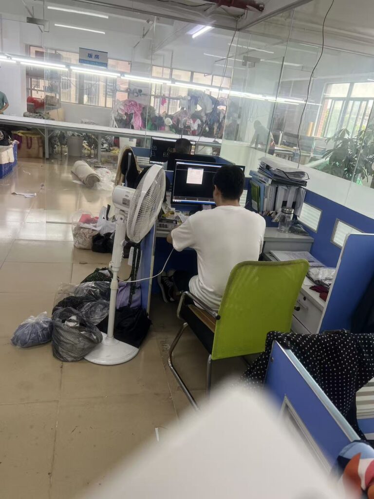 Staff member at a computer workstation beside a glass workshop partition