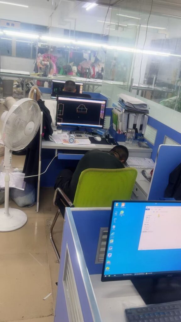 Computer workstations showing garment pattern outlines beside the sewing area