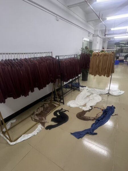 Burgundy and tan garments hanging on racks beside fabric pieces