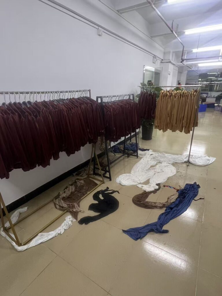 Burgundy and tan garments hanging on racks beside fabric pieces