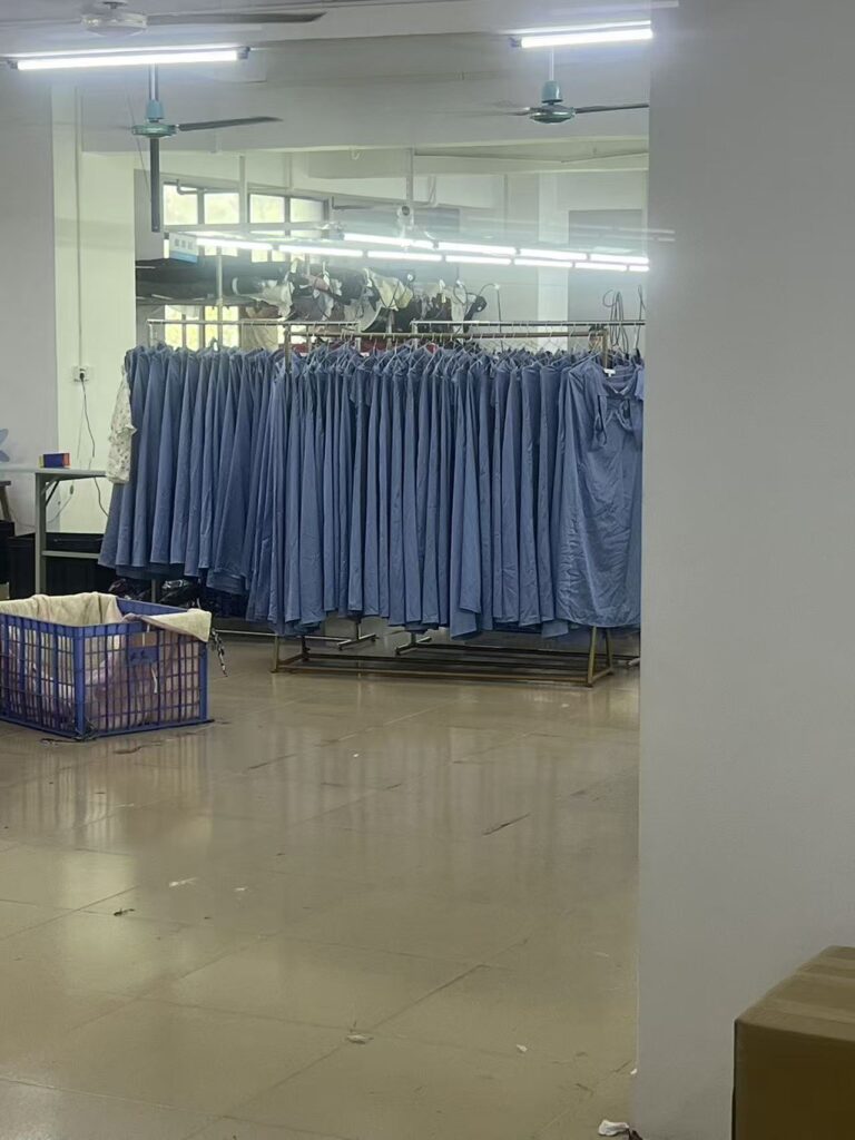 Row of blue garments hanging on a metal rack in the production workshop