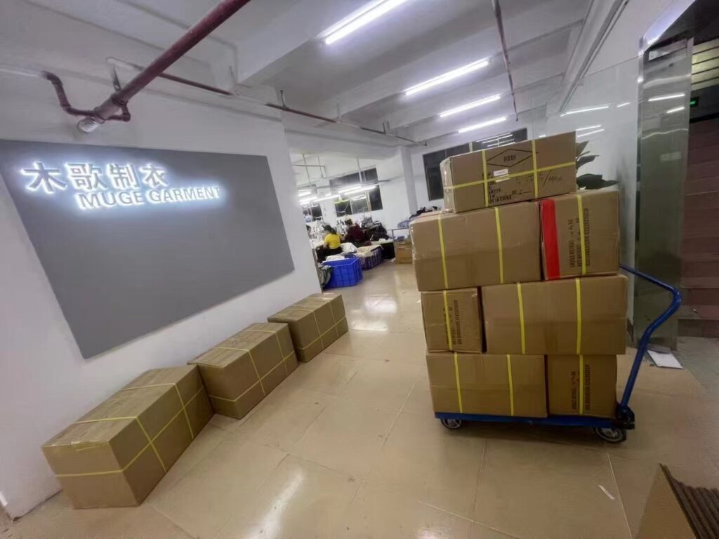 Sealed cartons stacked on a trolley beside the garment workshop reception wall