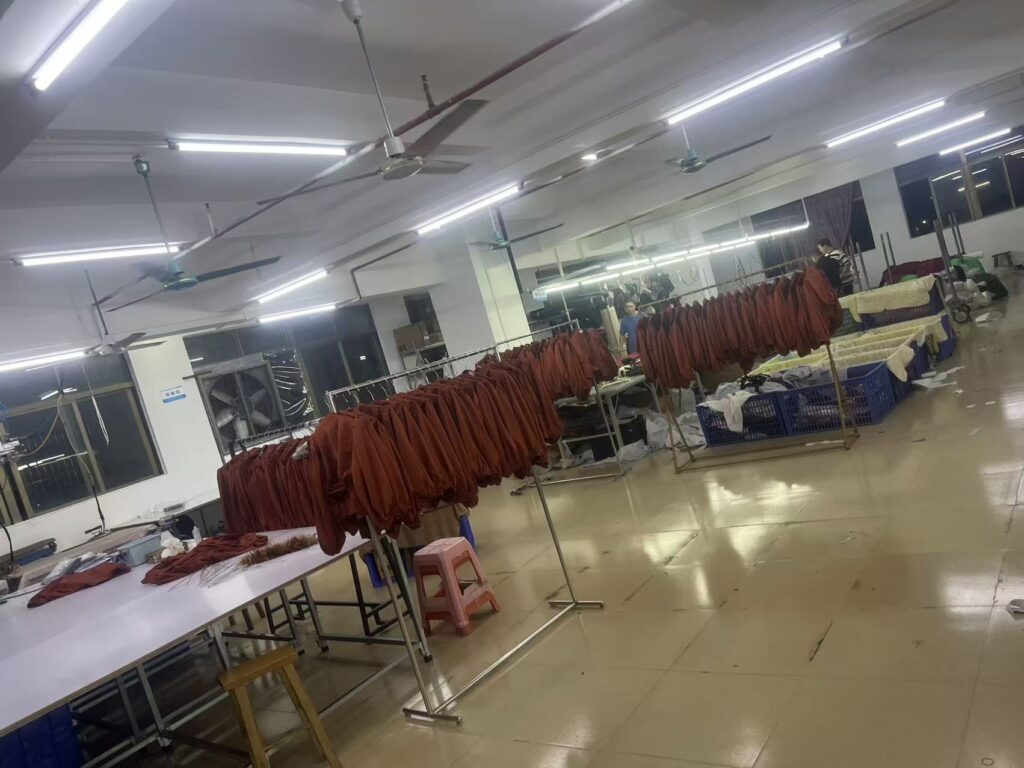 Rows of rust colored garments hanging on racks beside workshop tables