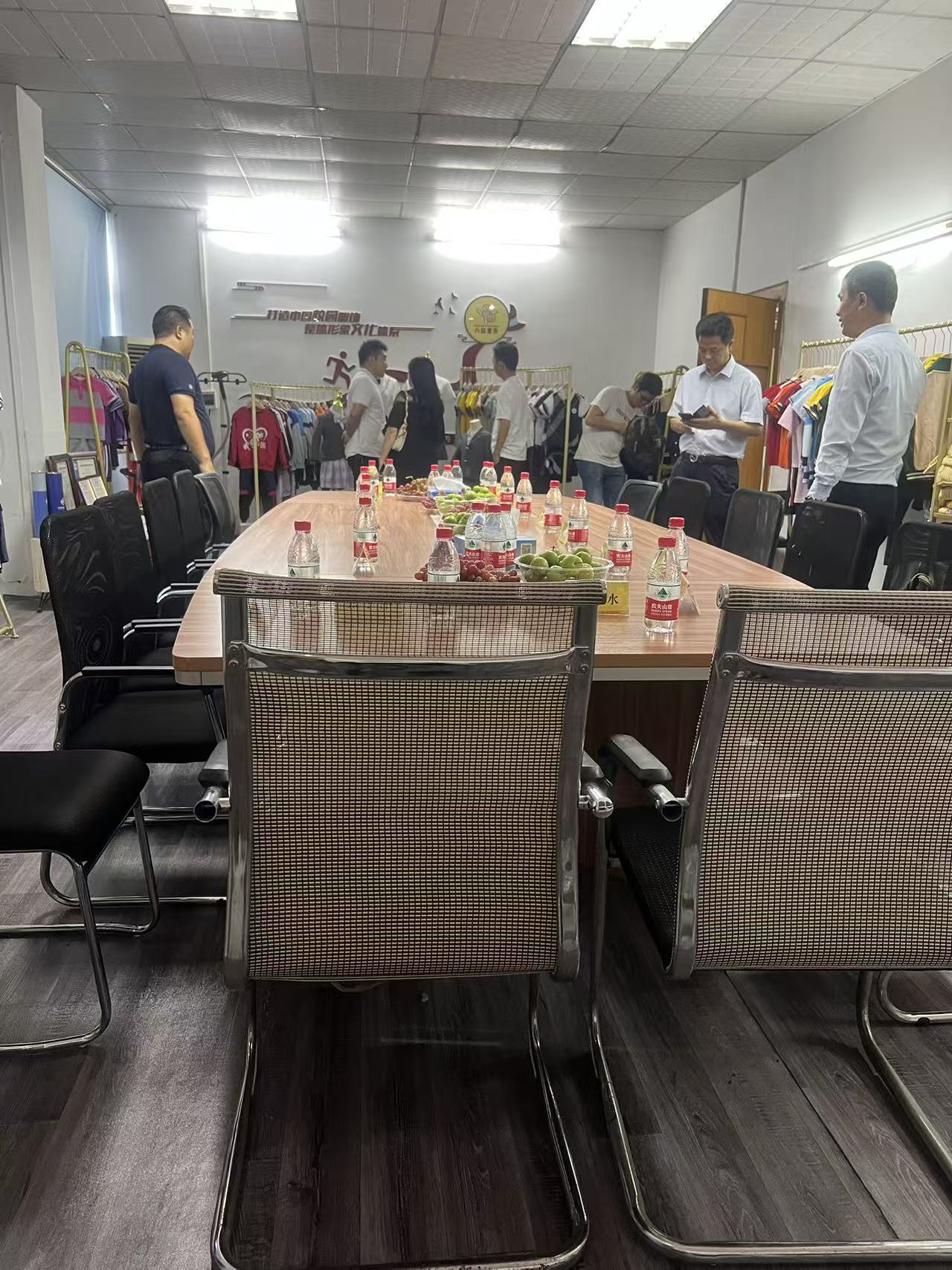 Meeting table and chairs surrounded by clothing racks in a garment showroom