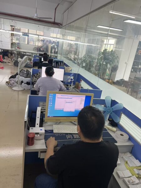 Staff member viewing garment pattern shapes on a computer in the workshop office