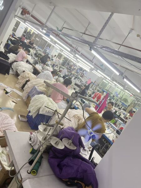 Rows of sewing workstations with garment bundles and fabric baskets