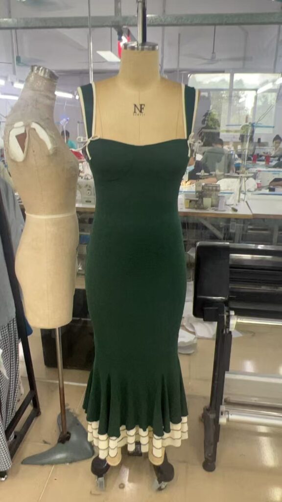 Dark green sleeveless dress with a flared hem and cream trim on a dress form
