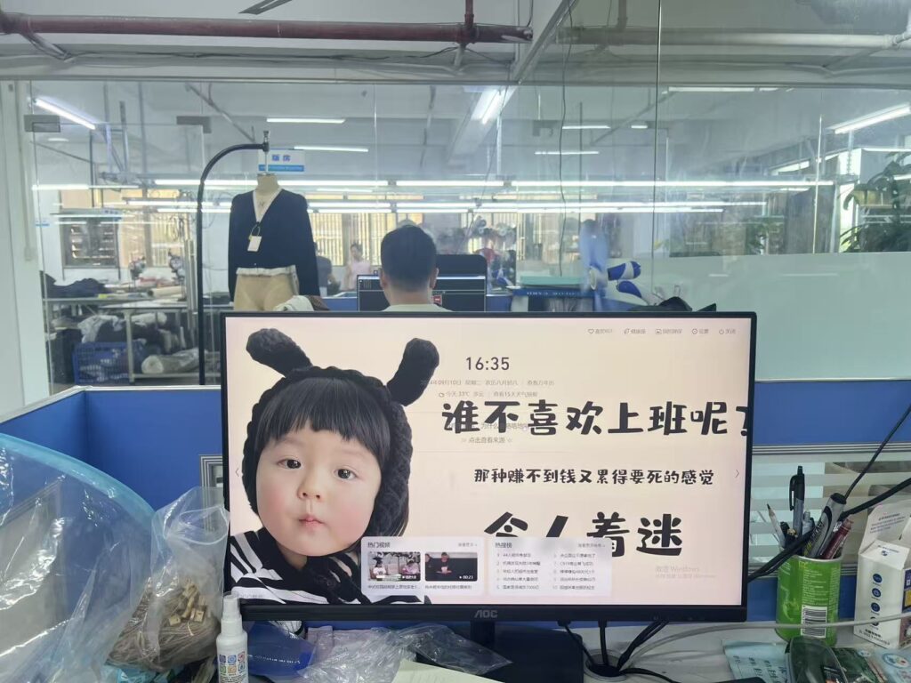 Office workstation beside a glass partition overlooking clothing production
