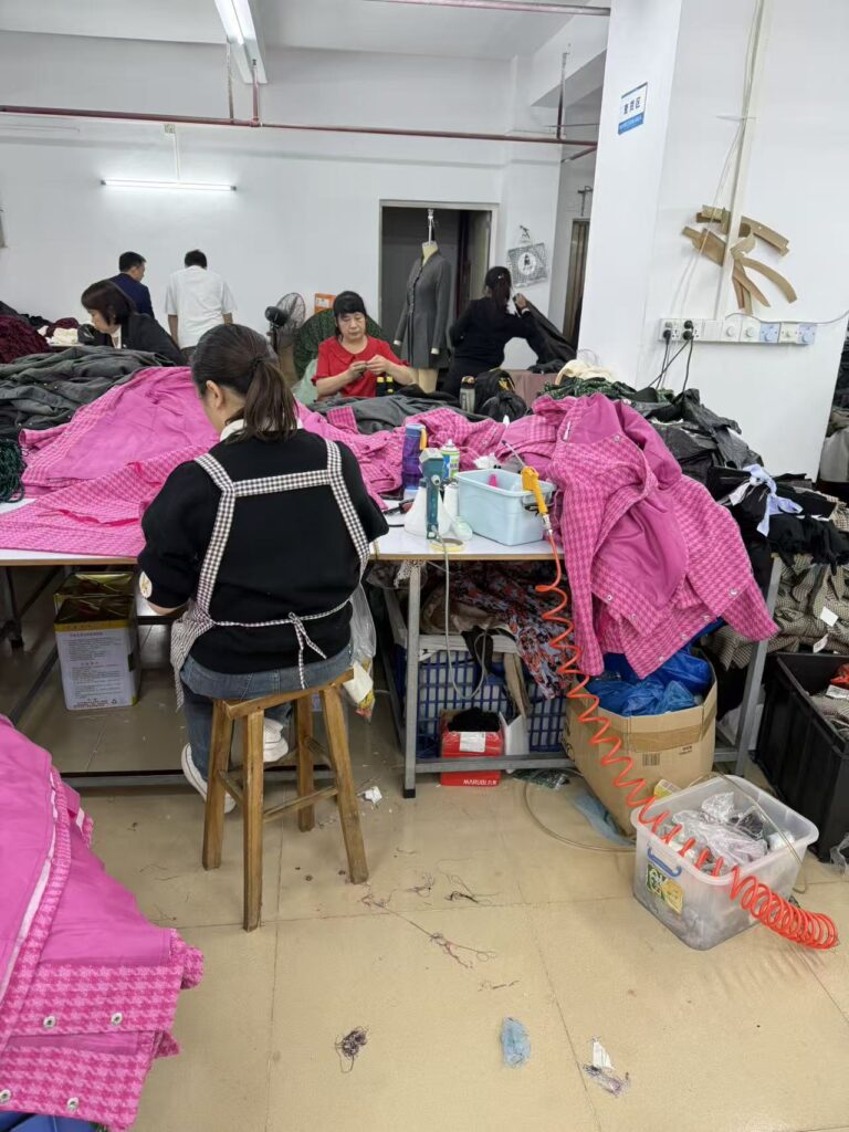 Workers handling pink gingham garments at shared production tables