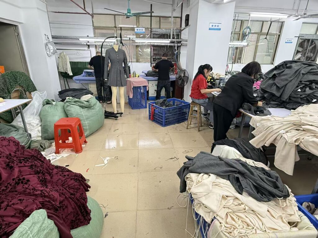 Workers sorting garments beside stacks of cream, burgundy and dark clothing