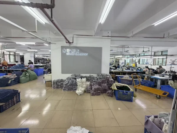 Apparel workshop with rows of sewing stations and bundled garments along a central aisle.