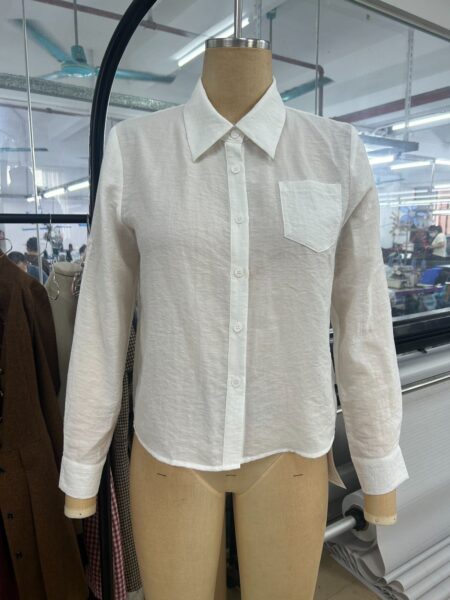 White long-sleeve button-front blouse with a pointed collar and chest pocket on a mannequin