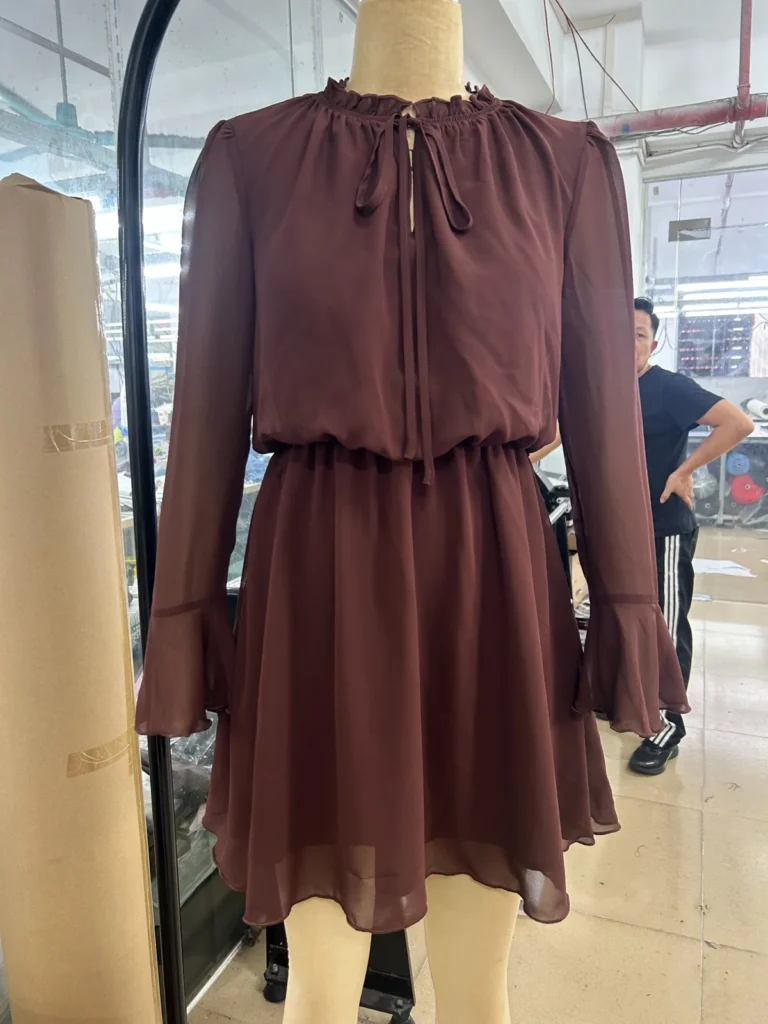 Burgundy tie-neck long-sleeve mini dress with a gathered waist on a mannequin
